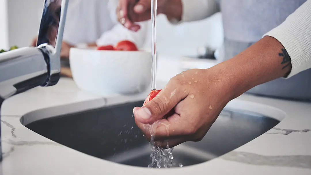 Rinsing Tomato Person rinsing a tomato in a kitchen sink
